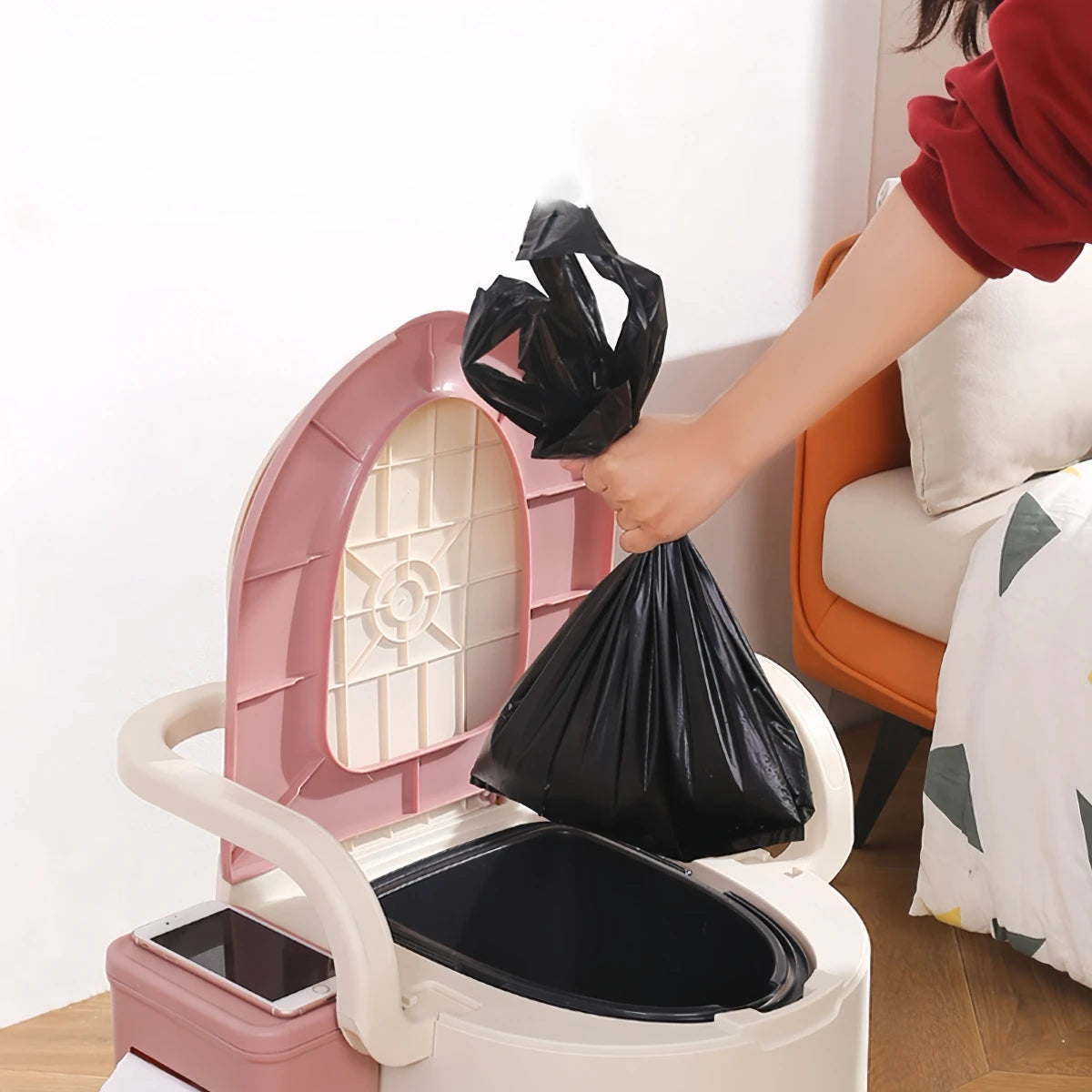 Person using Portable Toilet with Back Support Camping and Travel Use, placing a black trash bag inside.
